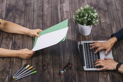 person typing laptop with his colleague holding blank white green blank paper wooden table 3 1 1