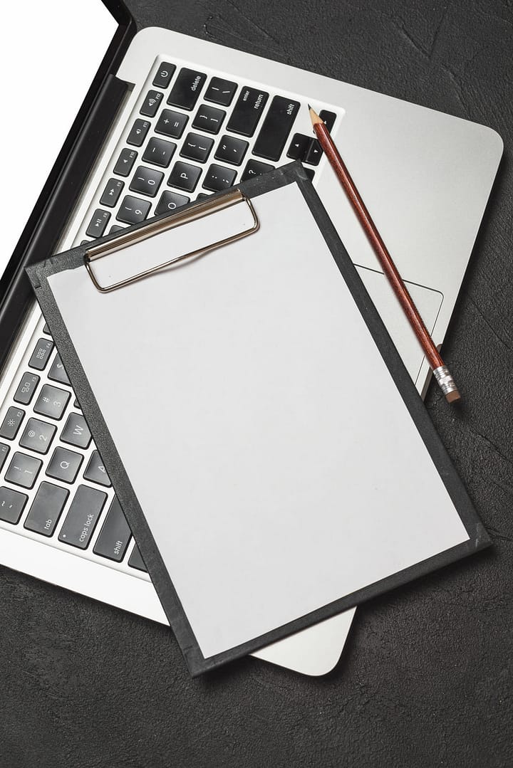 elevated view clipboard with blank white paper pencil laptop keypad 1 1